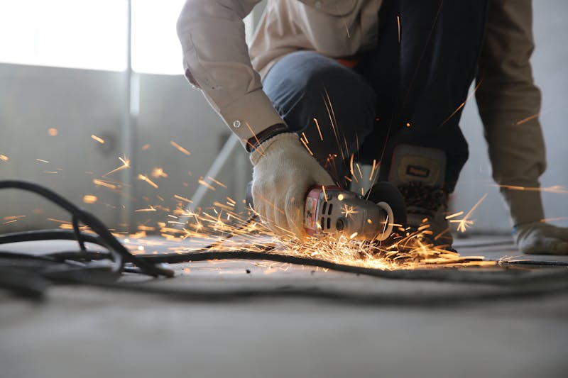 Construction worker performing metal grinding with safety equipment